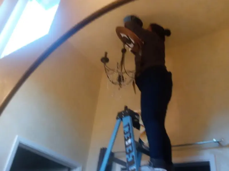 Electrician installing a chandelier in a Concord residence